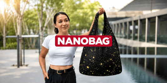 Kvinne holder et svart Nanobag-handlenett med stjernemønster utendørs.