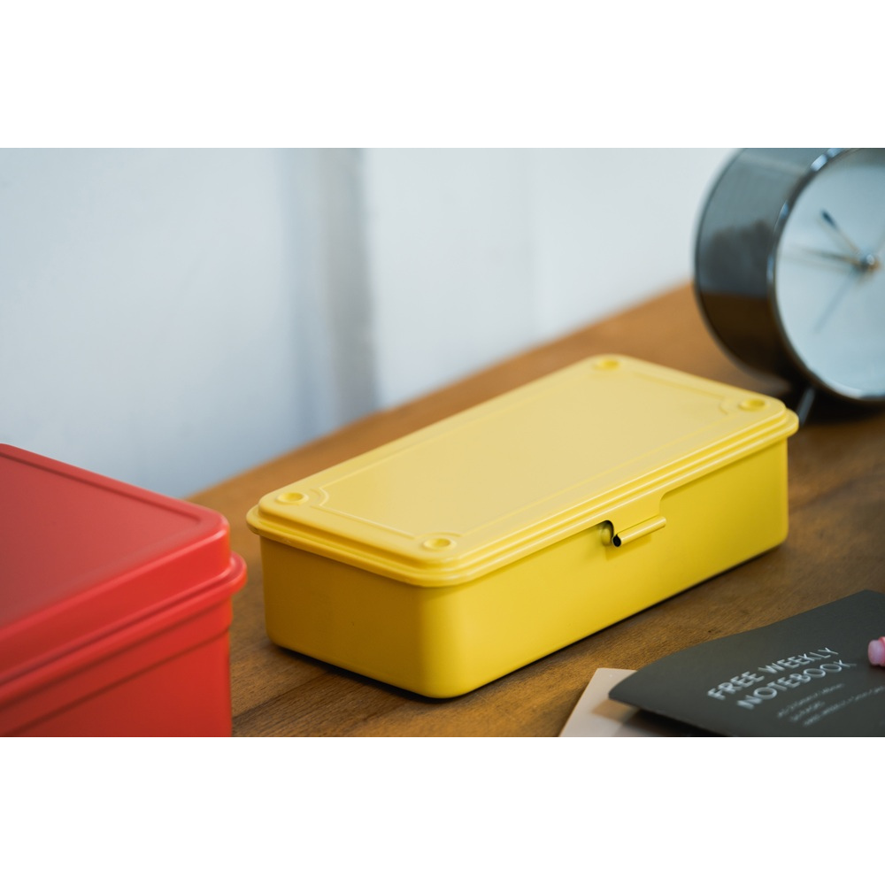 TOYO STEEL T-190 Italian Yellow, på et skrivebord ved siden av en rød boks